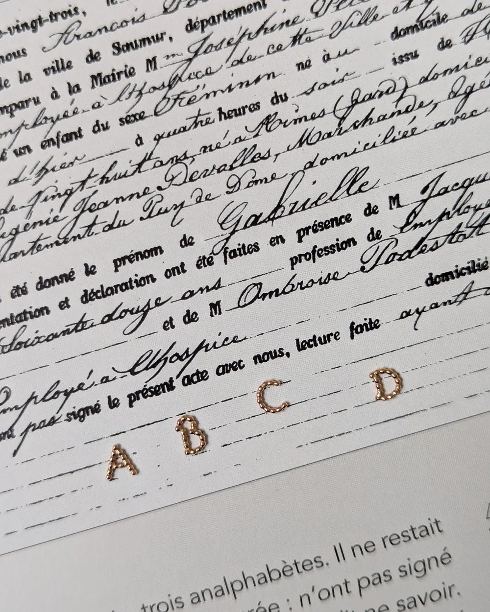 Lettres perlées posées sur un registre manuscrit ancien